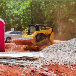 Construction site skid steer loader moving gravel, showing conditions where mobile oil change service trucks support field crews