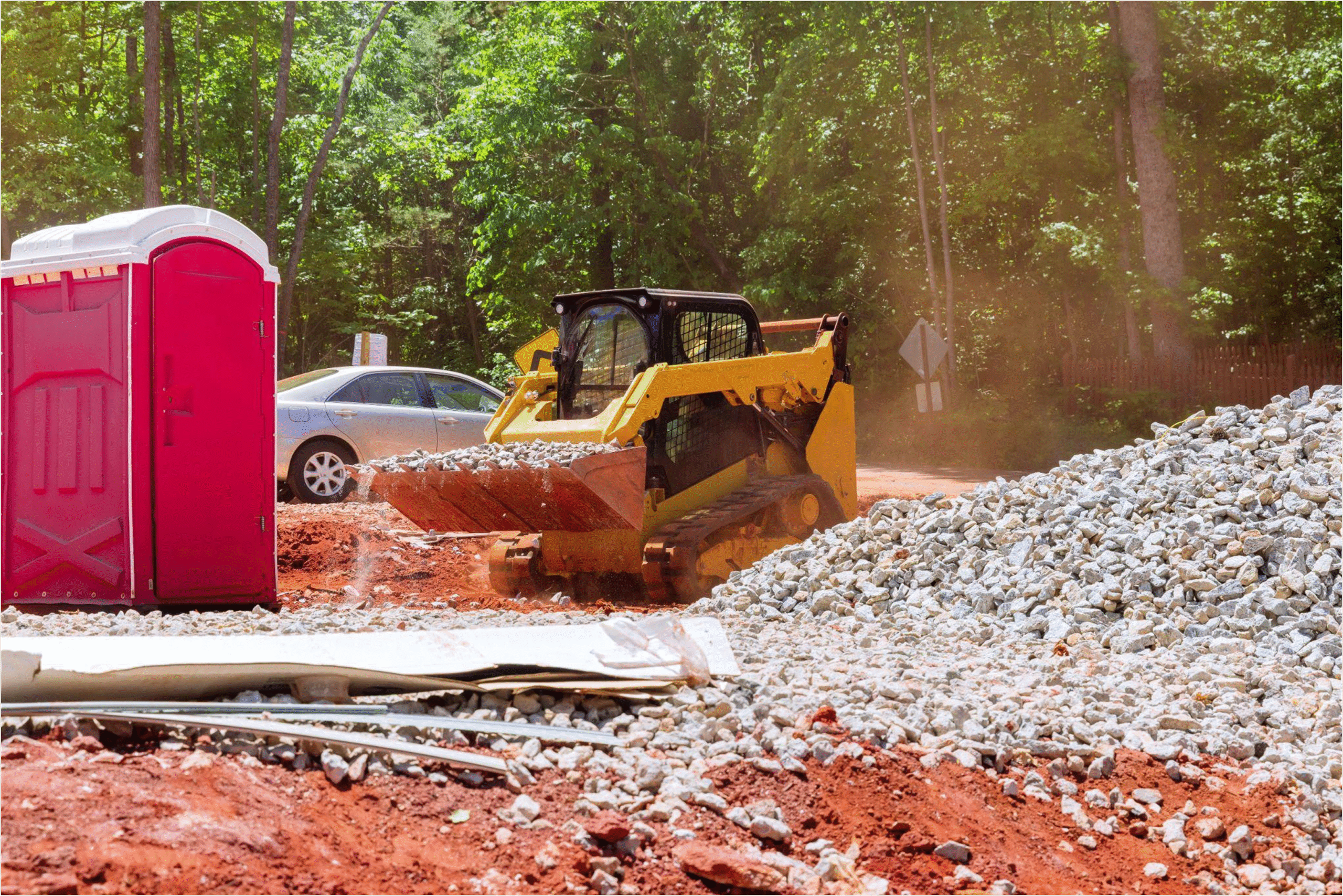 Construction site skid steer loader moving gravel, showing conditions where mobile oil change service trucks support field crews