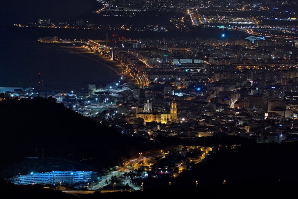 Aerial view of Málaga city with coastline and mountains at night