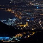 Aerial view of Málaga city with coastline and mountains at night