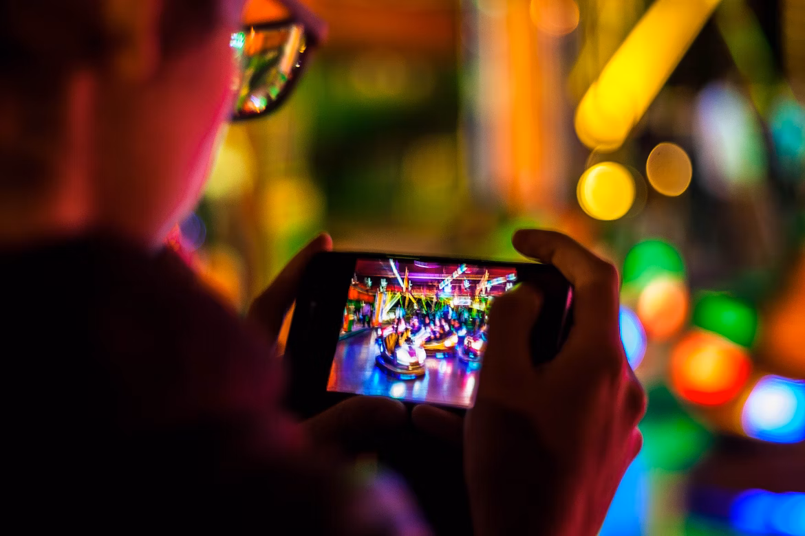 A man using a smartphone for mobile gaming, focused on the screen while playing or streaming a game.